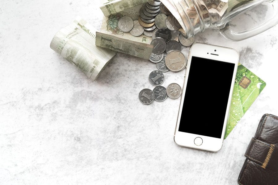 Imagen conceptual con dinero, teléfono y billetera sobre una mesa. Representa control de gastos y herramientas personales para manejar el dinero.