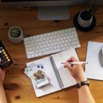 Persona sentada en un escritorio usando una calculadora para revisar sus finanzas personales y evitar errores financieros comunes en 2025